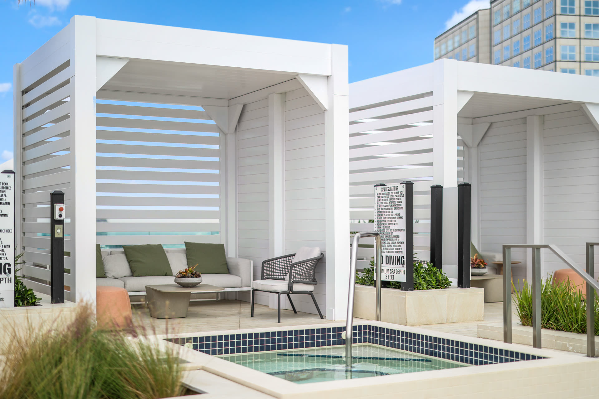 White Azenco R-BLADE pergola with privacy wall on a commercial pool deck &mdash; the specification-grade aluminum assembly Austin multifamily developers put on amenity decks that lease at premium rents.