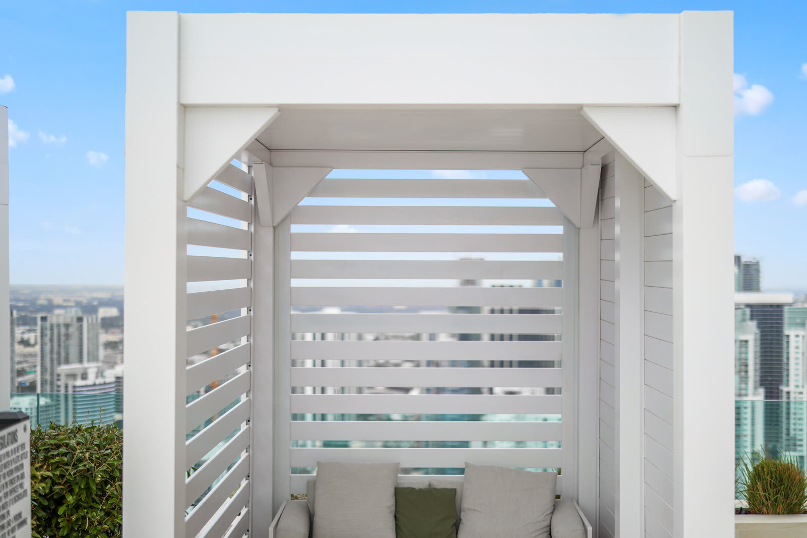 White Azenco R-BLADE louvered pergola shading a multifamily poolside patio with privacy wall — a fit for HOA and Class-A amenity decks.