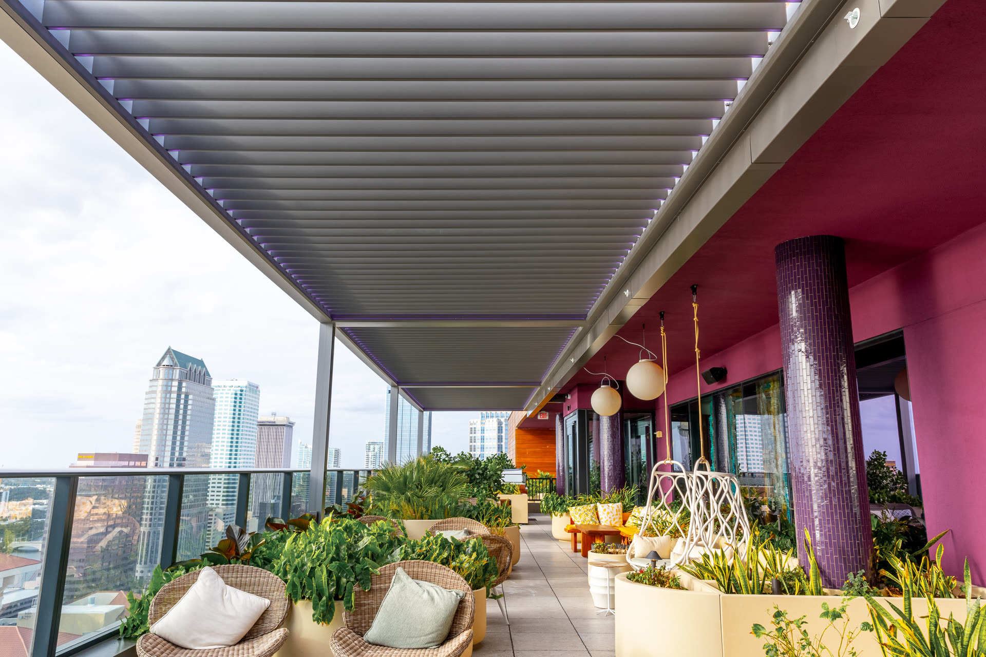 Gray Azenco R-BLADE pergola with closed louvers and integrated LED lighting over a high-rise rooftop terrace. Manufacturer-network installation photo, not a CCSI project.