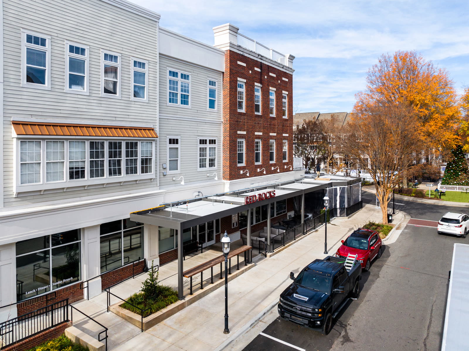 Streetfront restaurant patio covered by a louvered aluminum pergola along a mixed-use building. Manufacturer-network installation photo, not a CCSI project.
