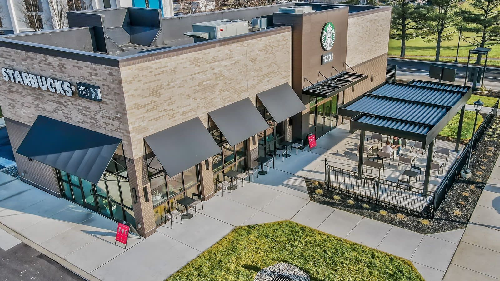 Alternate courtyard angle of a full-black Azenco R-BLADE installation — the specification vocabulary a food-hall entry court or urban mixed-use courtyard adopts as its architectural anchor.