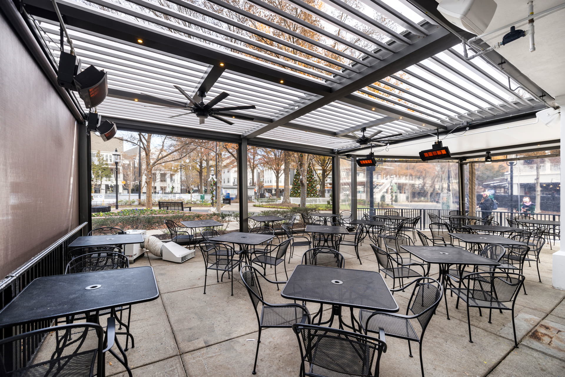 Azenco R-BLADE motorized louvered pergola on an all-season hospitality patio with fans and lighting. Manufacturer-network installation photo, not a CCSI project.