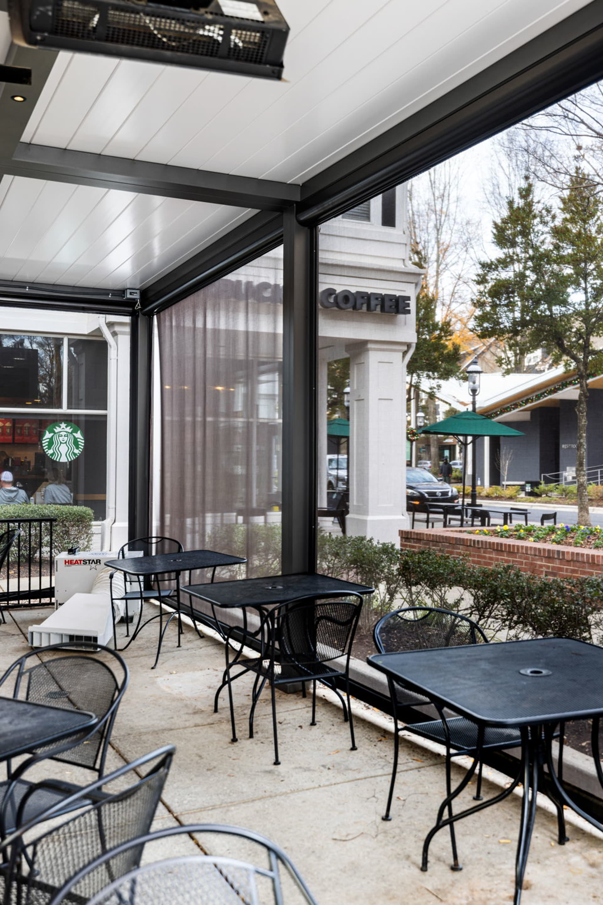 Azenco R-BLADE pergola with fans, recessed lighting, and heaters over a hospitality-grade seating area &mdash; the amenity vocabulary Austin office parks adopt for outdoor tenant plazas.