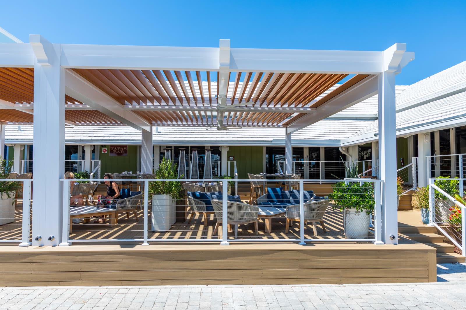 White R-BLADE pergola with ceiling fans on a hospitality amenity deck &mdash; the aesthetic Austin boutique hotels adopt to hold F&B revenue against weather.