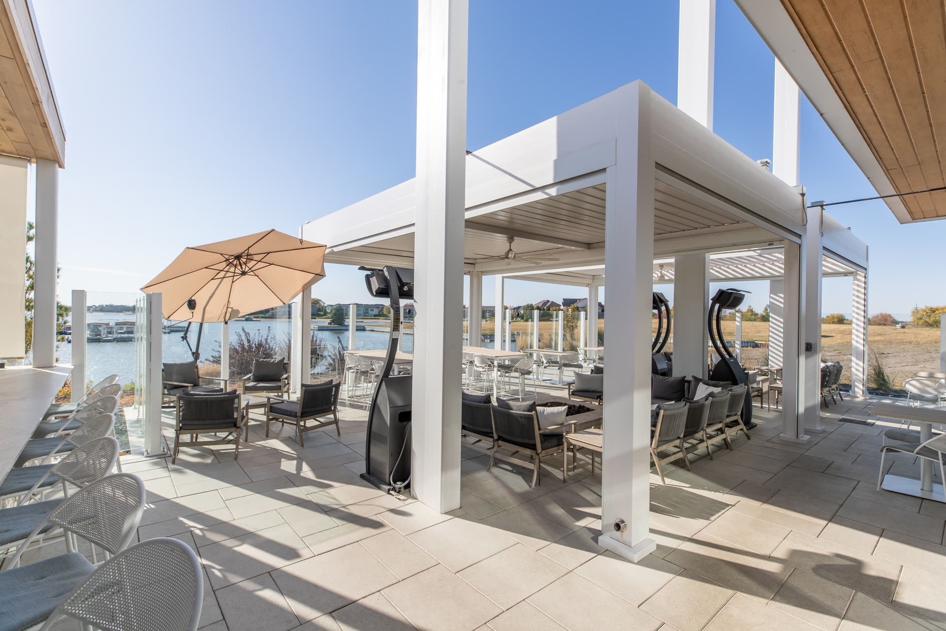 White commercial Azenco R-BLADE pergola with screens, fans, and integrated lighting on a hospitality-grade rooftop &mdash; the specification Austin hotel operators use for weather-adjustable rooftop bar and amenity deck programming.